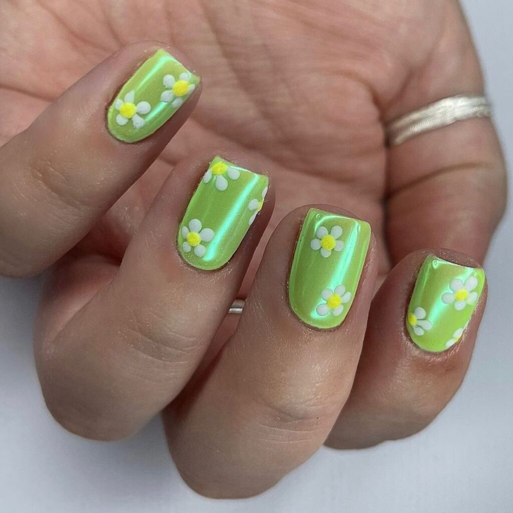 green chrome nails with little daisies painted on them