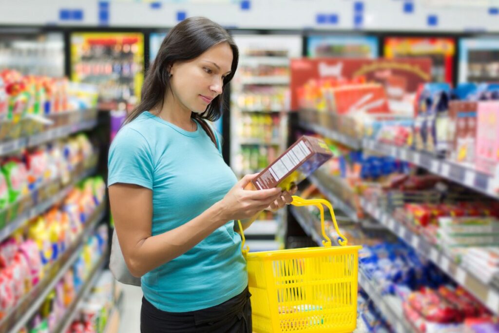 a woman standing in a grocery store reading a food label