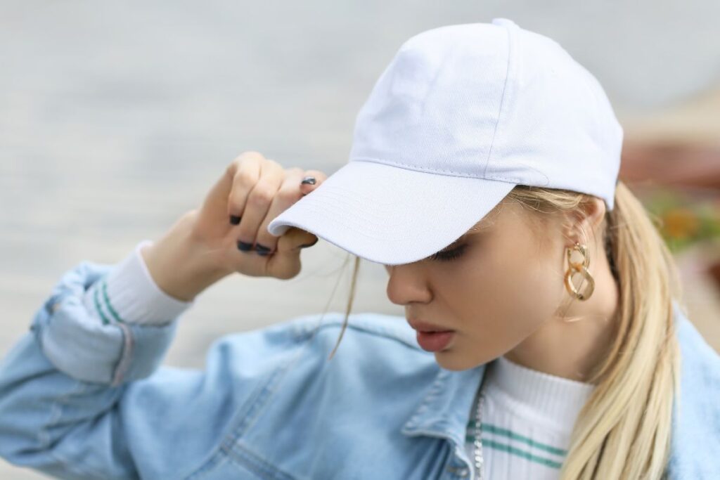 a girl in a white baseball hat with her hair in a ponytail