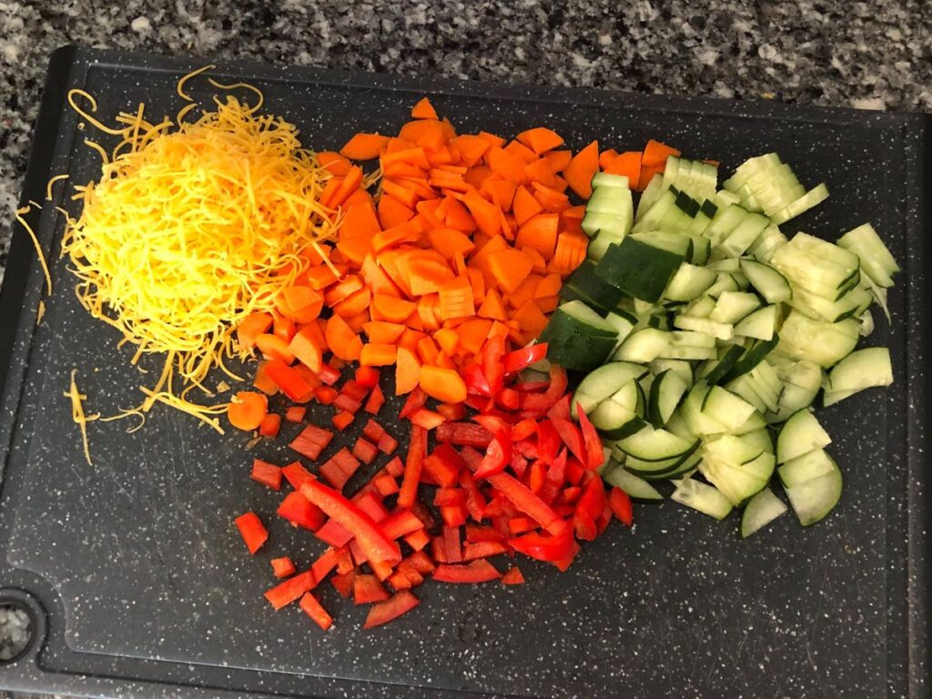 cut up veggies on a cutting board with some cheese